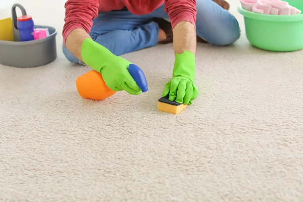 Young man cleaning carpet at home — Stock Photo, Image