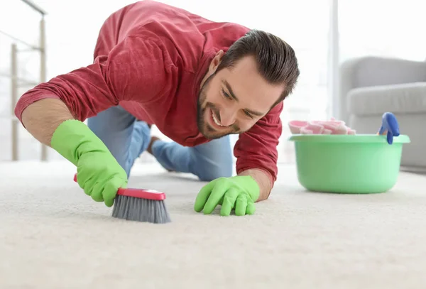 Jeune homme nettoyage tapis à la maison — Photo