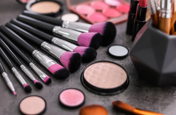Productos de maquillaje y pinceles sobre fondo gris — Foto de Stock