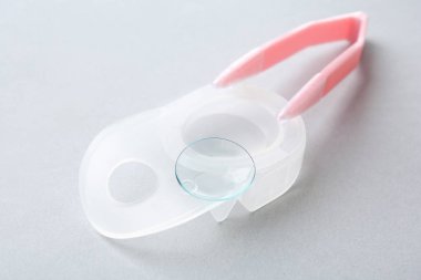 Kontakt lens ve ışık arka plan üzerinde cımbız ile paket