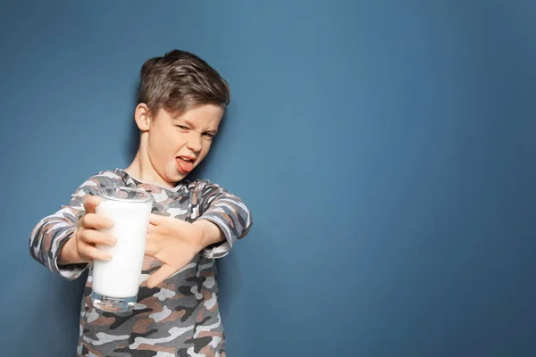 Niño con alergia láctea sosteniendo un vaso de leche sobre fondo de color — Foto de Stock