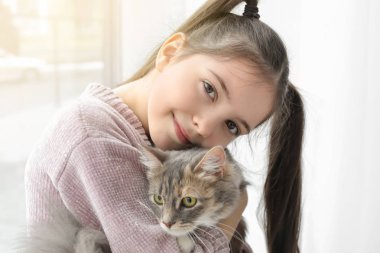 Sevimli küçük kız ile kedi evde pencere yakınındaki