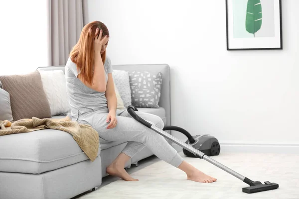 Cansado dona de casa sentado no sofá em vez de hoovering em casa — Fotografia de Stock