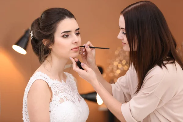 专业化妆艺术家与年轻新娘在沙龙工作 — 图库照片
