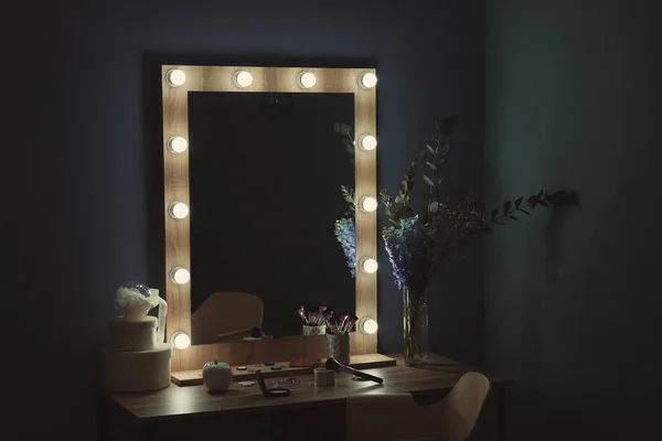 Стол с красивым зеркалом и косметикой в современной косметической комнате — стоковое фото