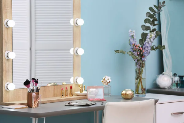 Cosmética decorativa y herramientas en tocador cerca del espejo en la sala de maquillaje — Foto de Stock