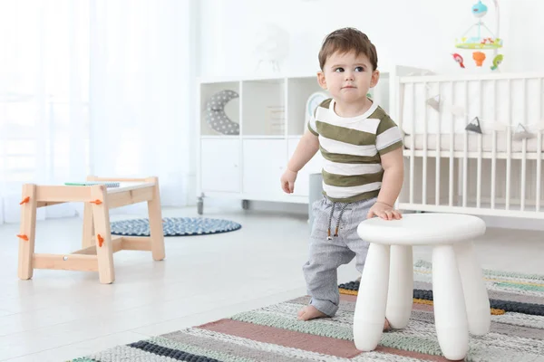 Lindo bebé sosteniendo el taburete en casa. Aprender a caminar — Foto de Stock