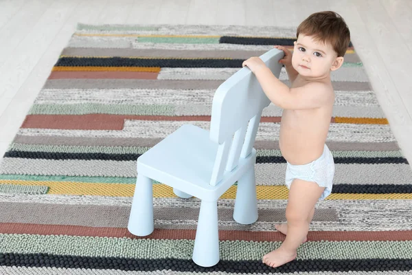 Cute baby holding on to chair at home.  Learning to walk — Stock Photo, Image