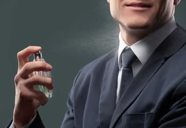 Hombre guapo en traje usando perfume sobre fondo oscuro, primer plano — Foto de Stock