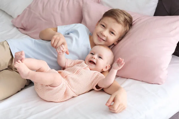 Bebê bonito com o irmão mais velho deitado na cama em casa — Fotografia de Stock