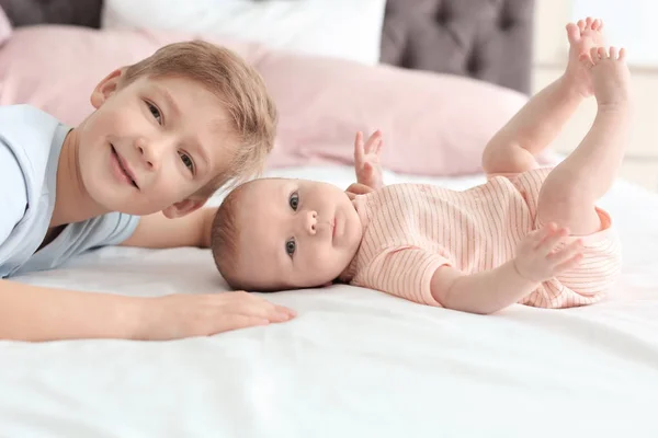 Evde yatakta yatarken ağabeyi ile şirin bebek — Stok fotoğraf