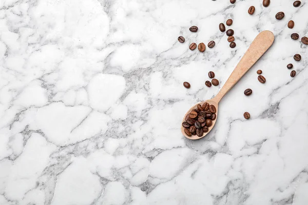 Cuchara con granos de café sobre fondo de mármol, vista superior — Foto de Stock