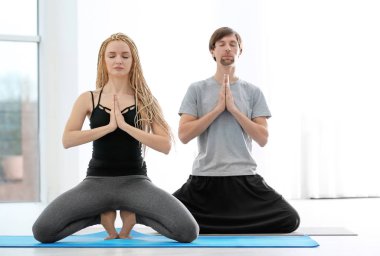 Genç adam ve kadın kapalı yoga uygulamak