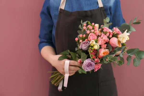 Kvinnliga florist med vacker bukett på färgbakgrund — Stockfoto