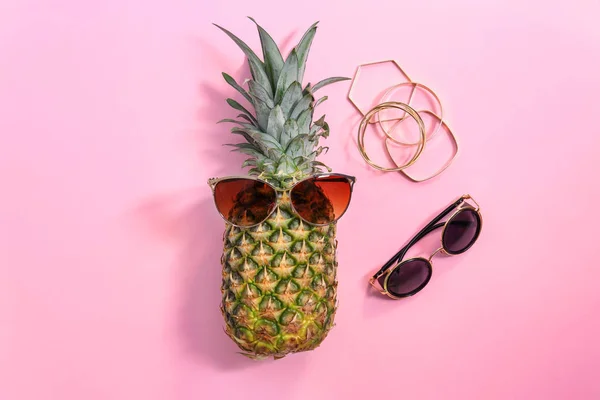 Ananas frais mûr avec des lunettes de soleil sur fond de couleur, vue de dessus — Photo