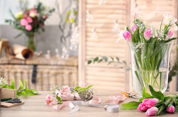 Рабочее место декоратора с красивыми цветами и незавершенным венком на столе — стоковое фото