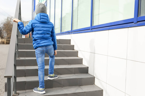 Lonely little boy on stairs outdoors. Autism concept