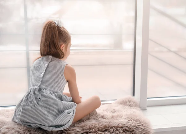 Одинокая маленькая девочка сидит у окна в помещении. Детский аутизм — стоковое фото