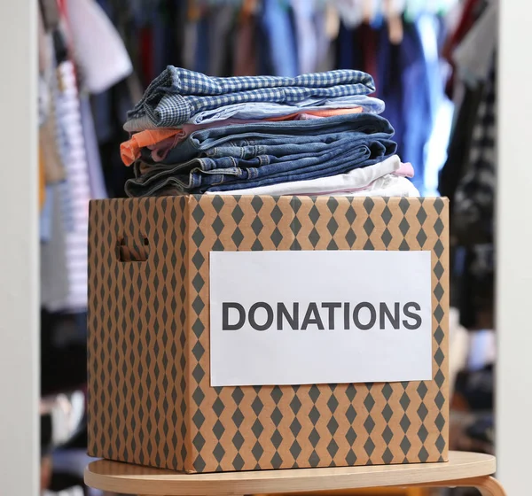 Caja de donación con ropa en la mesa en el interior — Foto de Stock