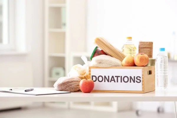 Caja de donaciones con productos alimenticios en la mesa en interiores —  Fotos de Stock