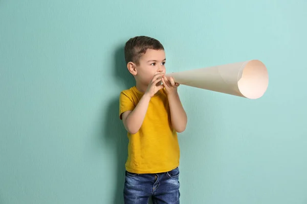 Чарівний маленький хлопчик з паперовим мегафоном на кольоровому фоні — стокове фото