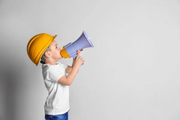 Adorabile bambino in hardhat con megafono su sfondo chiaro — Foto Stock