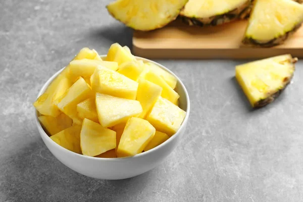 Cuenco con rodajas de piña fresca sobre fondo gris —  Fotos de Stock