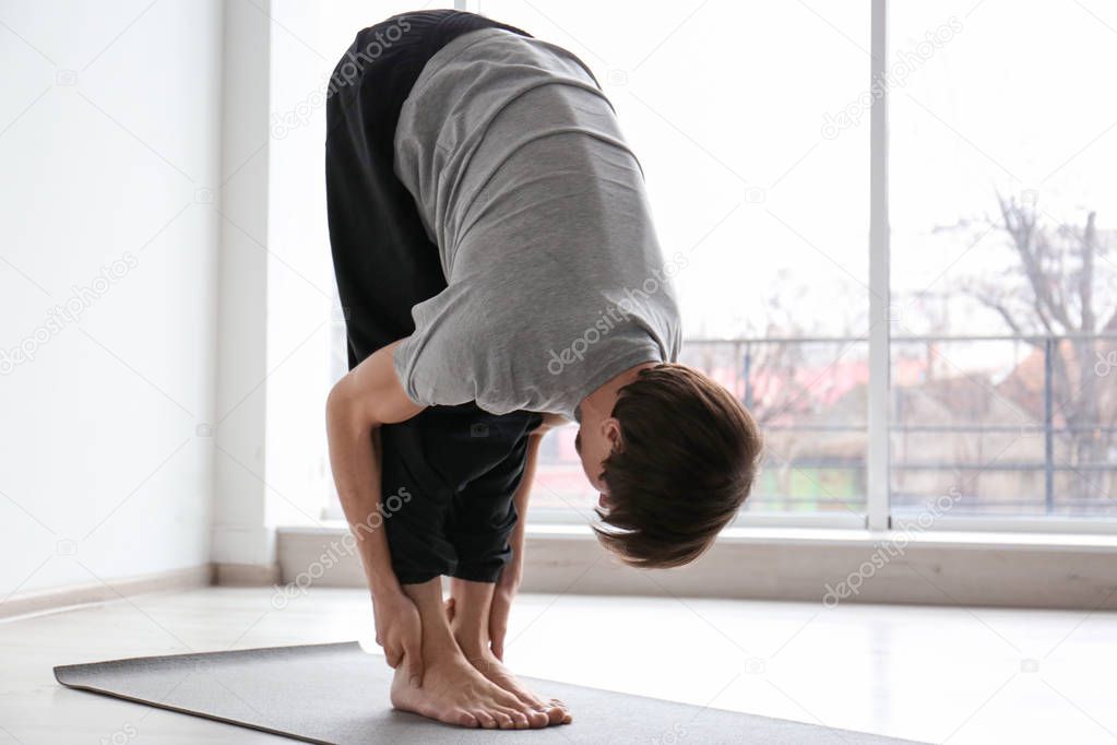 Young man practicing yoga indoors