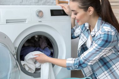 Evde çamaşır yıkayan genç bir kadın.