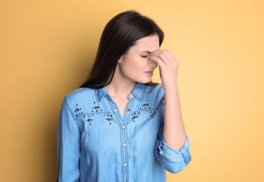 Genç kadın renk arka plan üzerinde baş ağrısı muzdarip