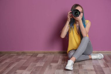 Genç kadın fotoğraf ile fotoğraf makinesi renk duvarının yakınında