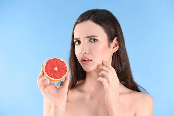 Tienermeisje met acne probleem bedrijf grapefruit tegen een achtergrond met kleur — Stockfoto
