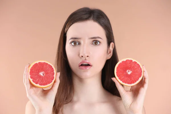 Teenager-Mädchen mit Akne-Problem hält Grapefruit vor farbigem Hintergrund — Stockfoto