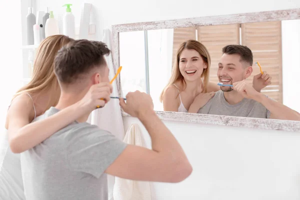 Jovem casal escovar os dentes juntos no banheiro — Fotografia de Stock