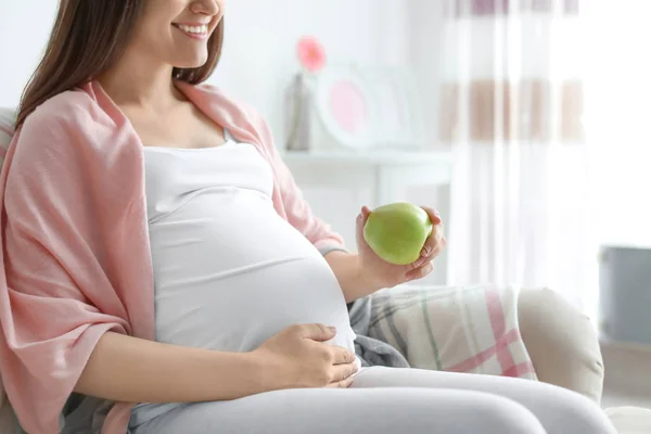 Jovem grávida segurando maçã em casa — Fotografia de Stock