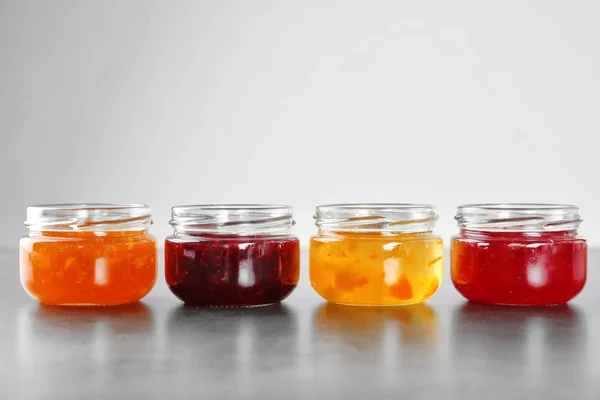 Üvegek különböző édes lekvárral, a szürke háttér — Stock Fotó