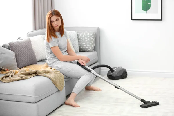 Cansado dona de casa sentado no sofá em vez de hoovering em casa — Fotografia de Stock