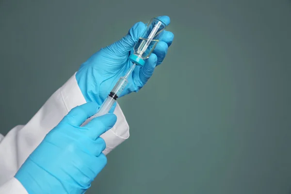 Врач со шприцем и лекарствами для вакцинации на цветном фоне — стоковое фото