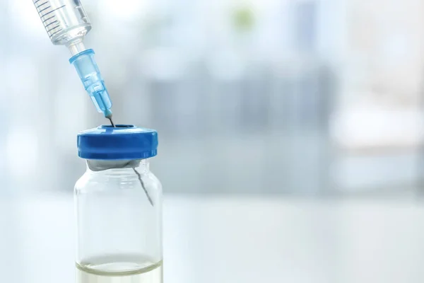 Vial with vaccine and syringe on blurred background — Stock Photo, Image