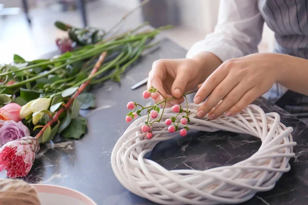 Kwiaciarnia kobiet, tworząc piękny wieniec przy stole, zbliżenie — Zdjęcie stockowe