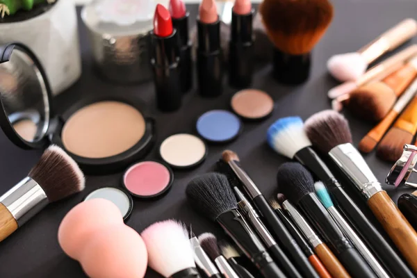 Diferentes escovas de maquiagem e produtos cosméticos em fundo preto — Fotografia de Stock