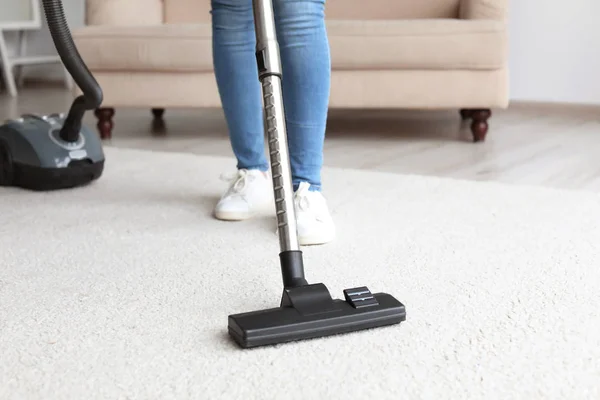 Wanita membersihkan karpet dengan vakum di ruang tamu — Stok Foto