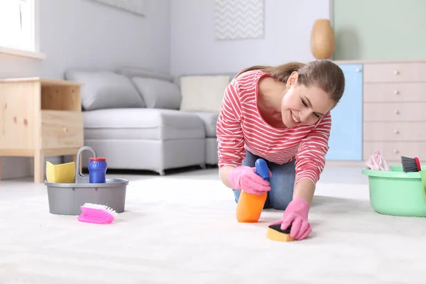 Jonge vrouw schoonmaak tapijt thuis — Stockfoto