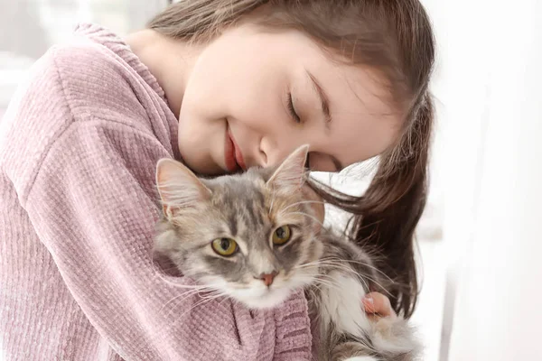 Roztomilá holčička s kočkou doma okna — Stock fotografie