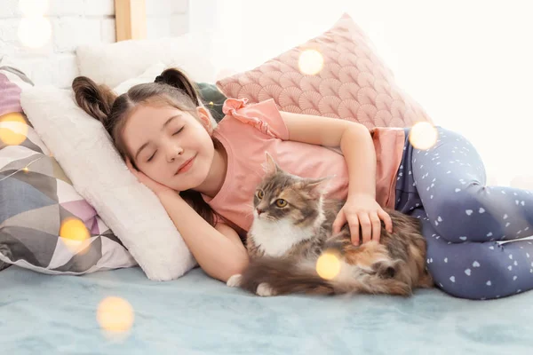Carino bambina con gatto sdraiato sul letto a casa — Foto Stock