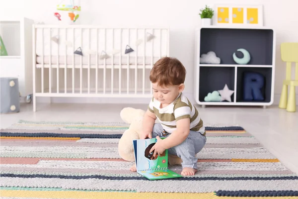 Niedliches Baby sitzt mit Buch zu Hause auf dem Boden — Stockfoto