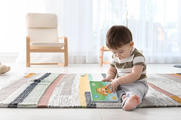 Bébé mignon assis sur le sol avec livre à la maison — Photo