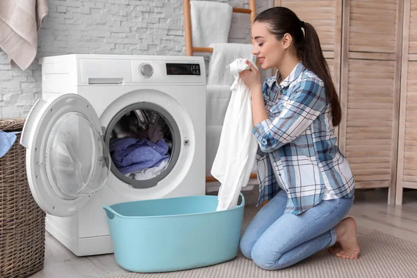 Jovem mulher fazendo lavanderia em casa — Fotografia de Stock