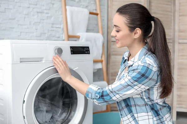 Jovem mulher fazendo lavanderia em casa — Fotografia de Stock