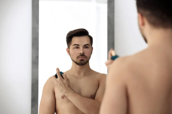 Hombre guapo usando perfume delante del espejo — Foto de Stock